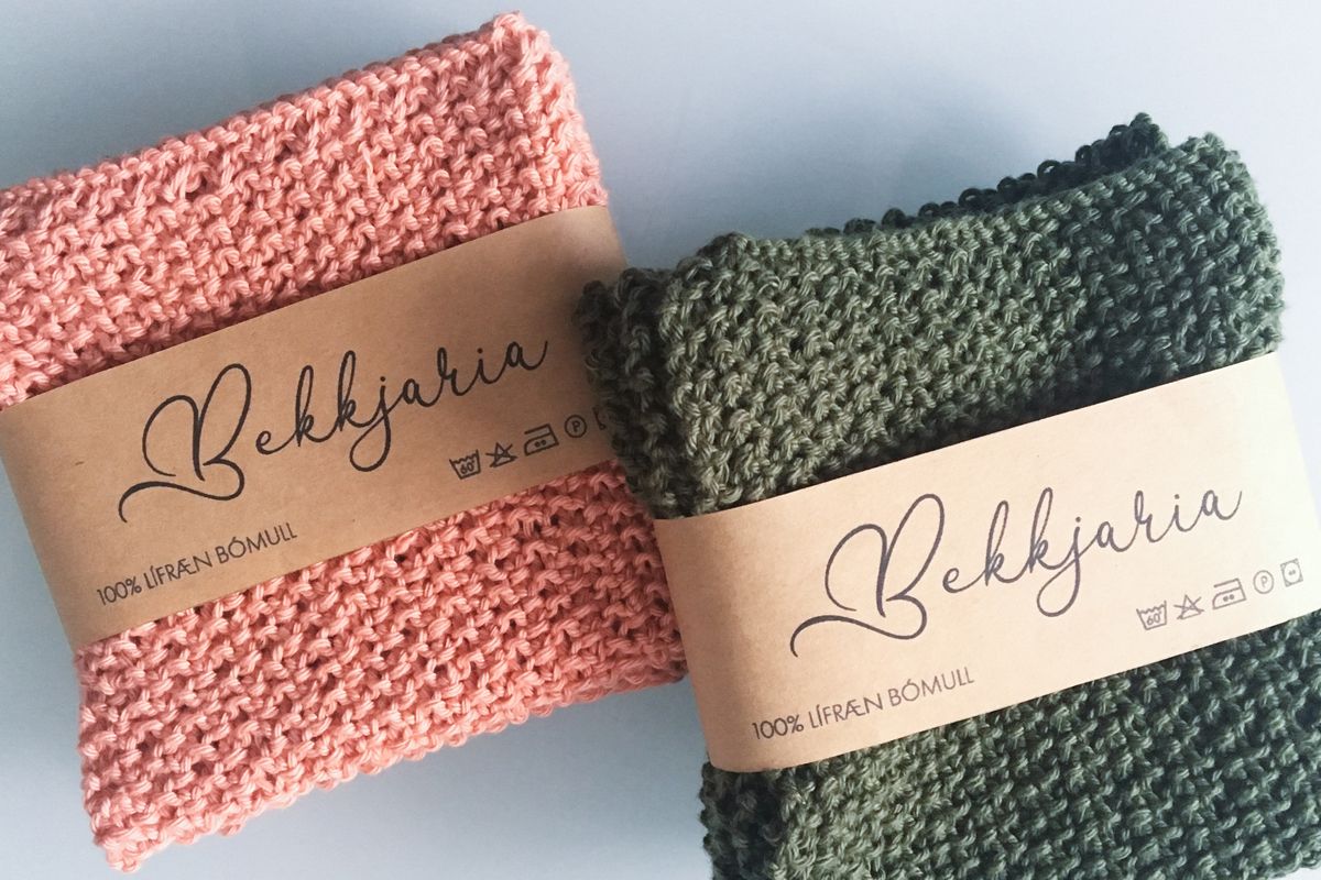 Two sweaters each wrapped in a paper sleeve with a clothing packaging design applied.